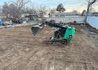 Compact loader grading bare soil to prep a yard for new landscaping