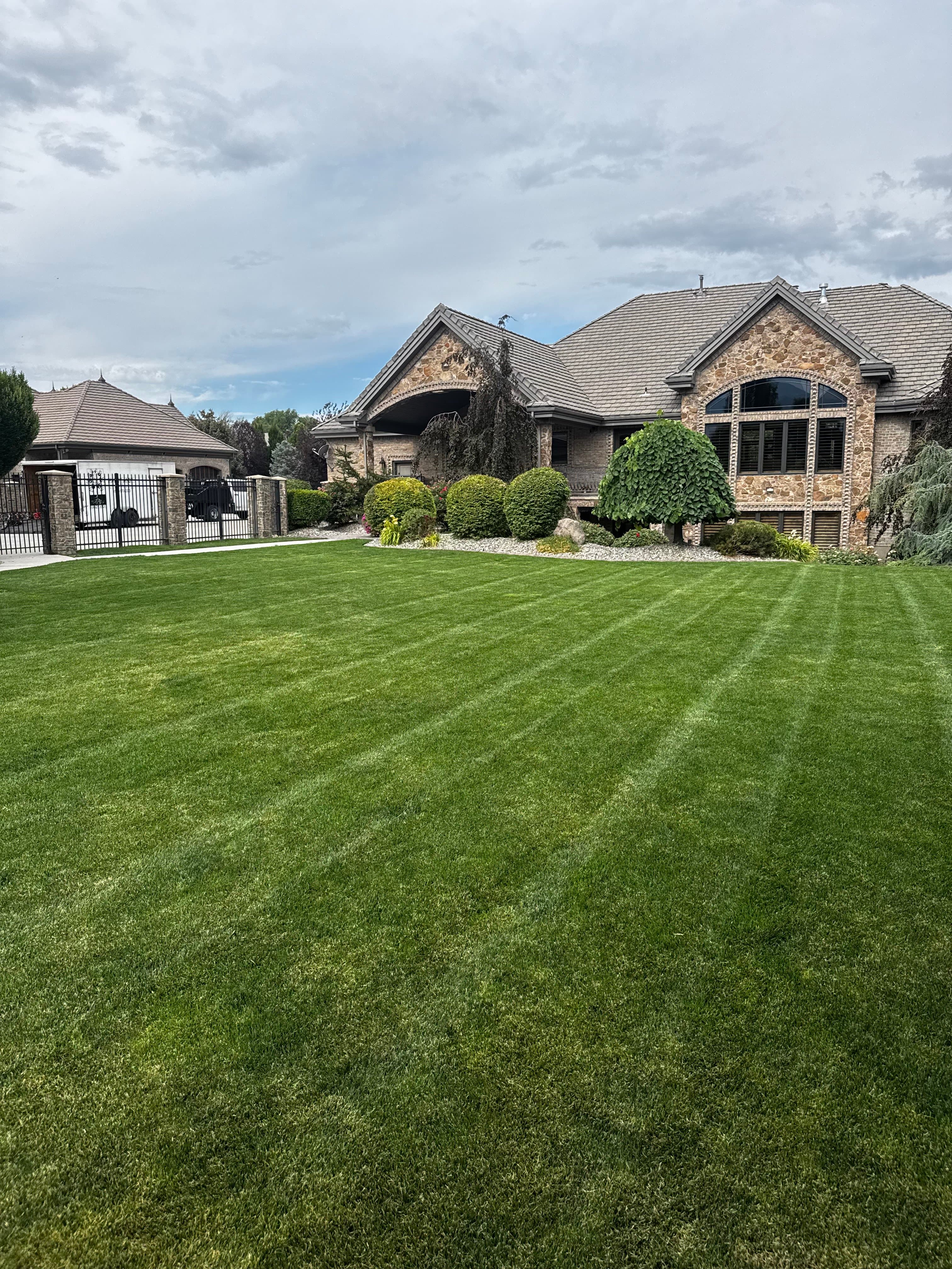Freshly striped lawn in front of a large stone home