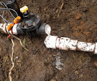 Exposed PVC sprinkler line being repaired in a dug-out section of lawn