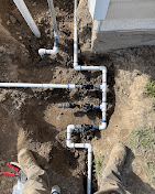 New sprinkler valve manifold installed in an open trench next to a home