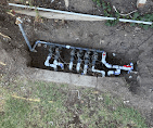 Multi-zone sprinkler valve manifold plumbed in an open trench